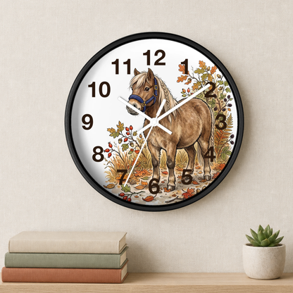Round wall clock with a black frame and a printed illustration of a brown horse on a white face, styled on a beige wall above a shelf with books and a small succulent.