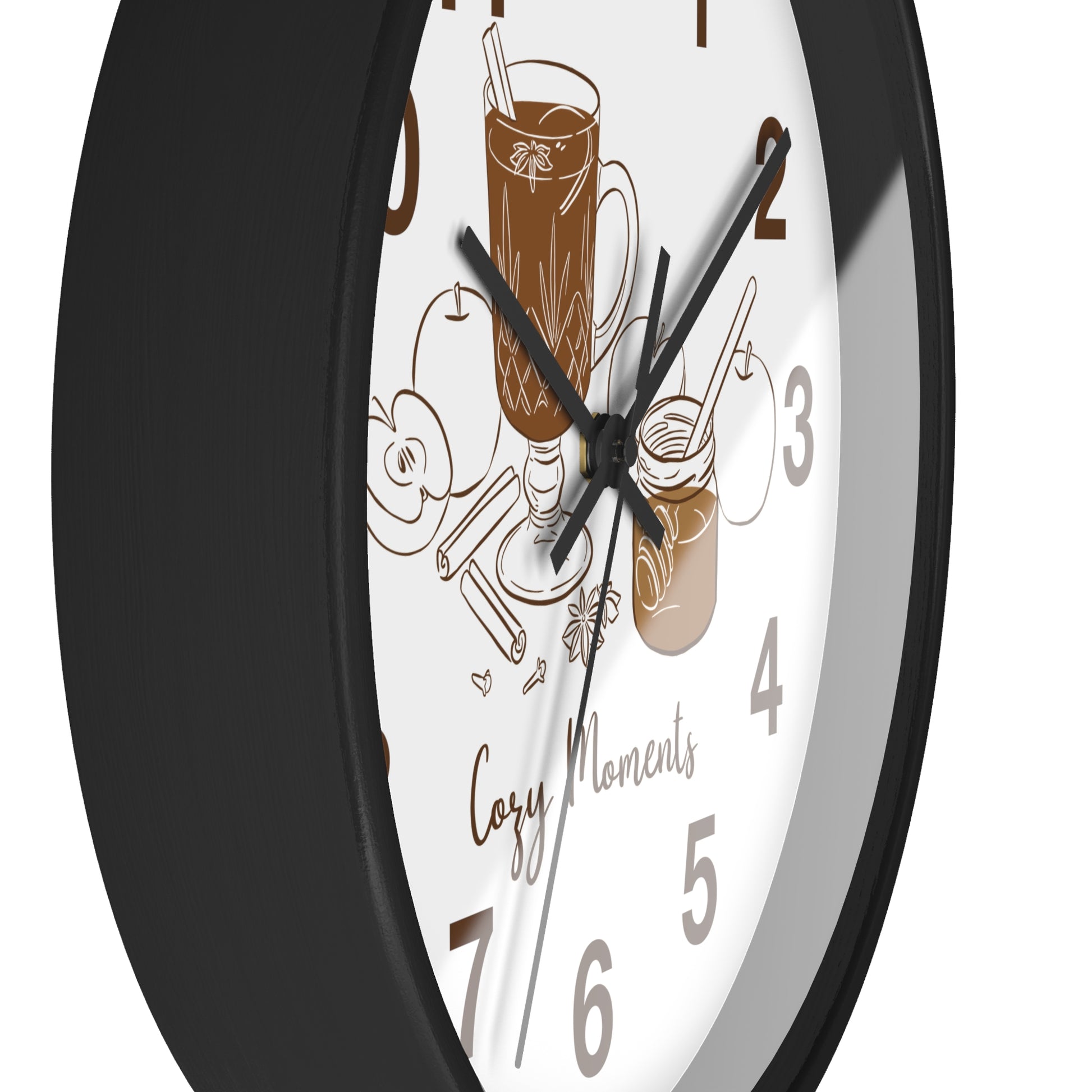 A close-up of a round wall clock with a black frame and a white face featuring brown coffee-themed illustrations, including a mug, a jar, and the words 'Cozy Moments'.