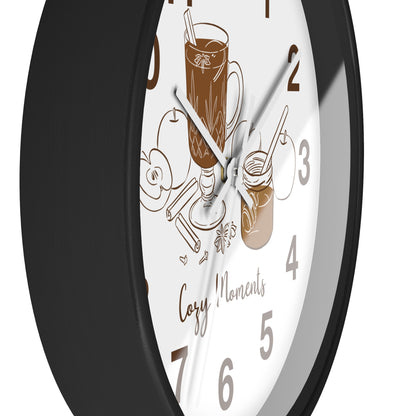 A close-up of a round wall clock with a black frame and a white face featuring brown coffee-themed illustrations and the words 'Cozy Moments'.