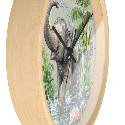 A round wall clock with a light natural wood frame and a printed elephant scene on the face. The clock shows a gray elephant spraying water in a tropical jungle setting, with black hands and partial black Arabic numerals visible against a plain white background.