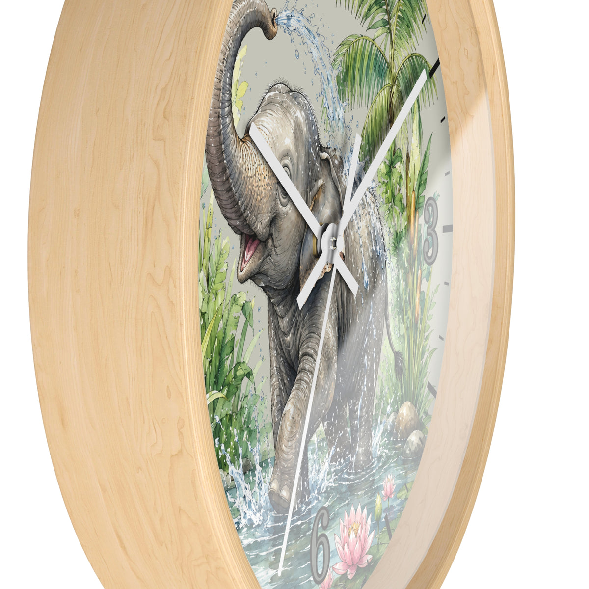Round wall clock with a light natural wood frame and a printed elephant scene on the face. The artwork shows a gray elephant spraying water, with palm leaves, water, and partial black numerals visible.