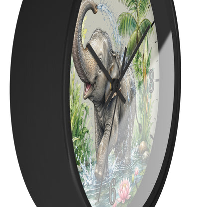 A round wall clock with a black frame and a printed elephant scene on the face. The artwork shows an elephant standing in water with palm leaves and tropical foliage in the background.