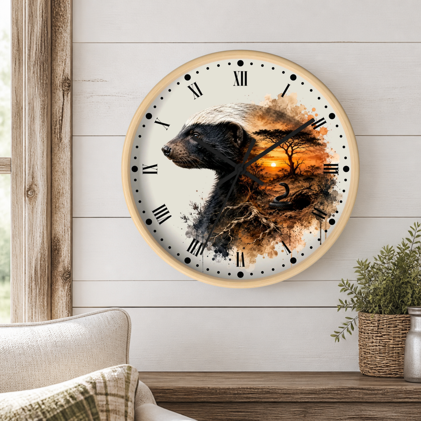 A round wall clock with a light wood frame hangs on a white shiplap wall above a wooden table. The clock face features a detailed illustration of a badger in profile blending into a forest scene with an orange sunset and tree silhouette.