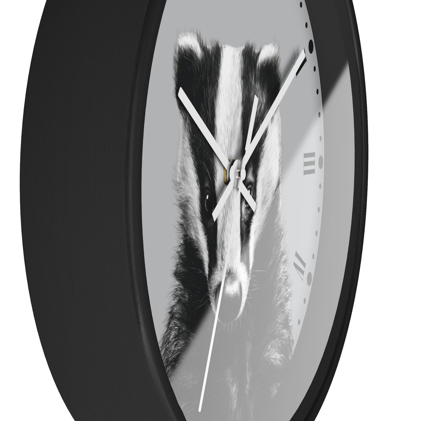 A round wall clock with a black outer frame and a grayscale printed face showing a badger face, with white clock hands and minimal Roman numerals.