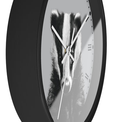 A round wall clock with a black outer frame and a grayscale printed face showing a badger face, with white clock hands and minimal Roman numerals.