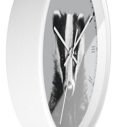 A white oval wall clock featuring a black and white photograph of a badger on the clock face, with white hands and minimal Roman numerals.