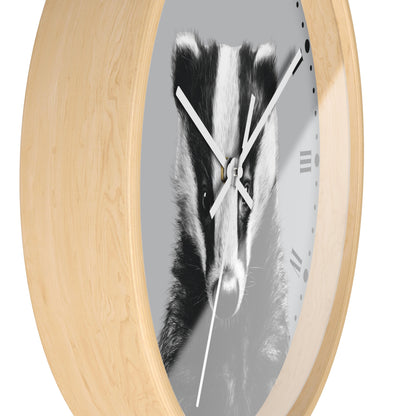 Round wall clock with a light natural wood frame and a grayscale print of a badger face on the dial, with white hands and black Roman numerals.
