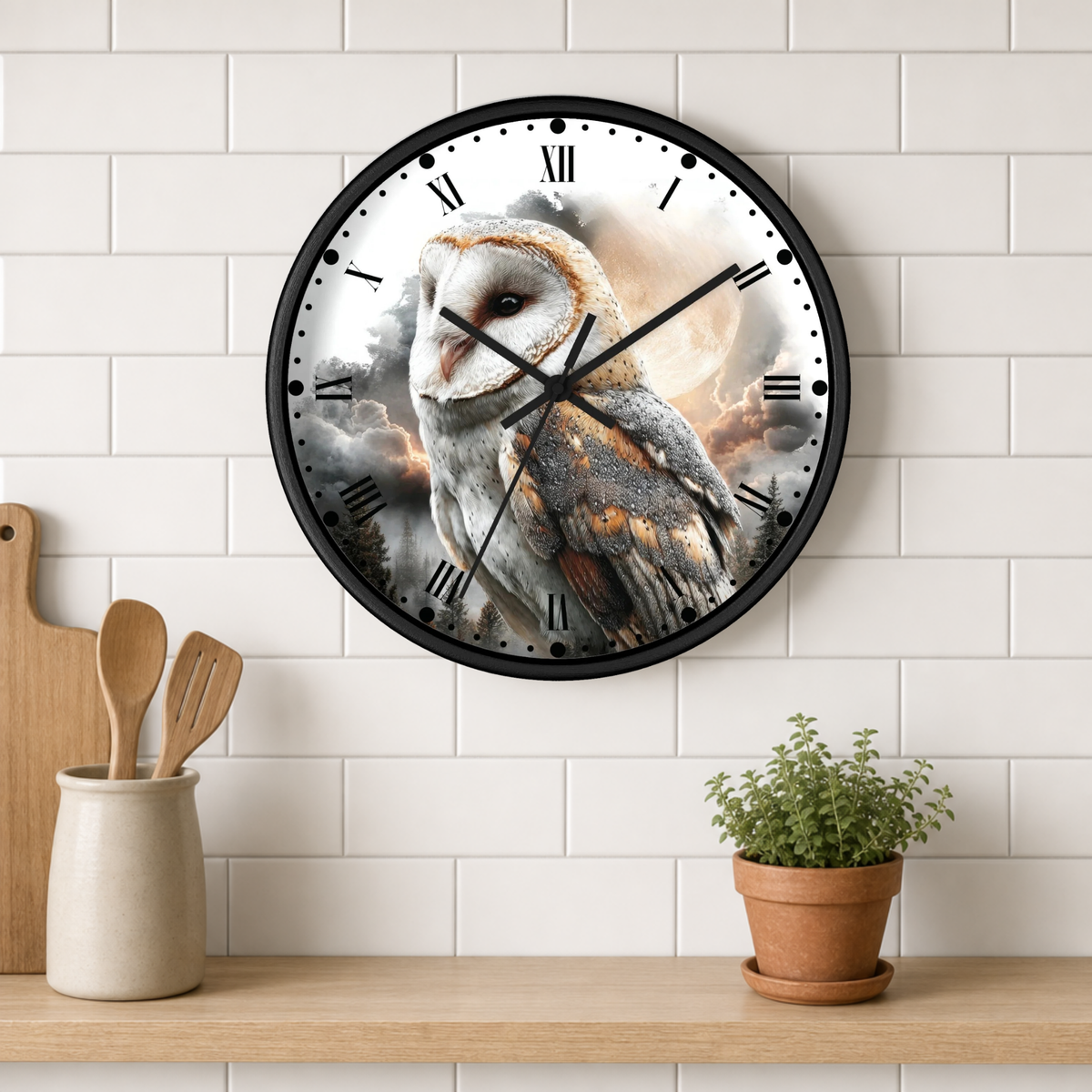 A round wall clock with a black frame and a printed barn owl design on the face, mounted on a white subway-tile wall above a wooden shelf with kitchen utensils and a potted plant.