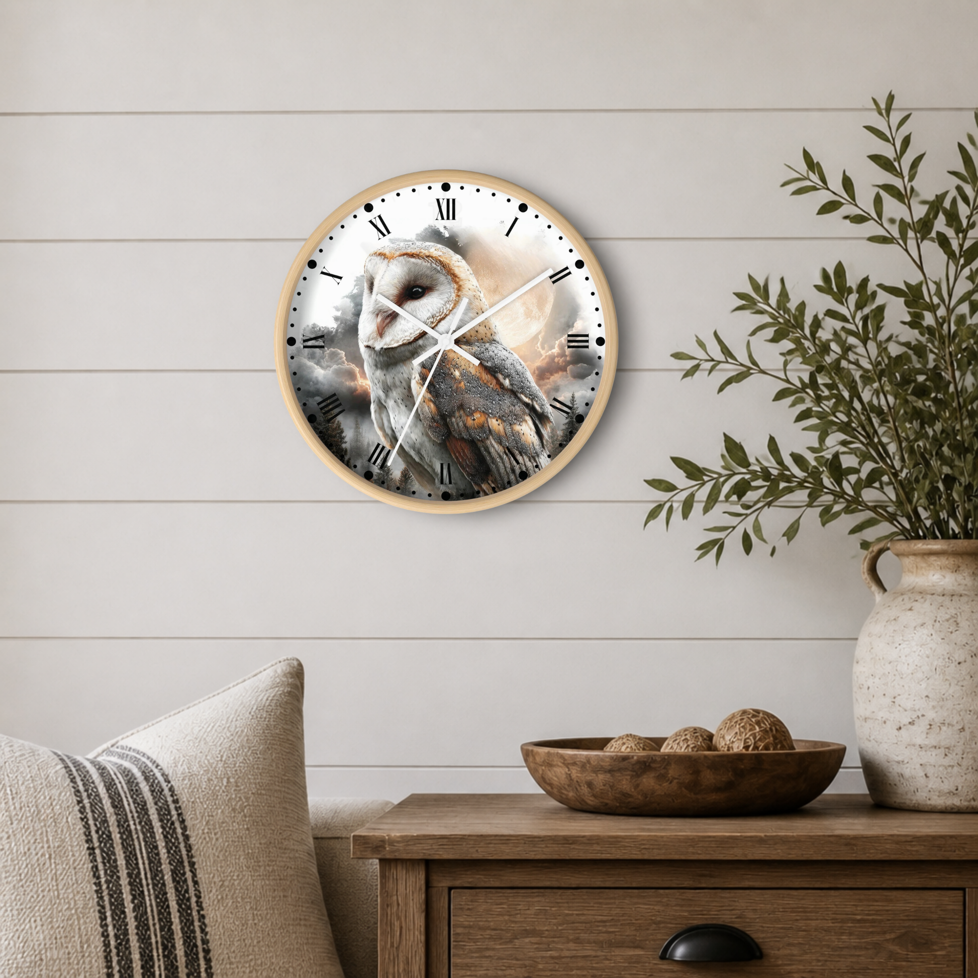 Round wall clock with a barn owl illustration and a light wood frame, displayed on a white shiplap wall above a wooden side table with a vase and bowl.