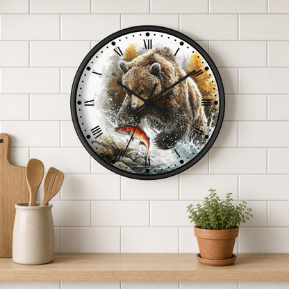 A round wall clock with a black frame hangs on a white subway tile wall above a wooden shelf. The clock face features a detailed illustration of a brown bear catching a red-orange fish, with black Roman numerals and black hands.