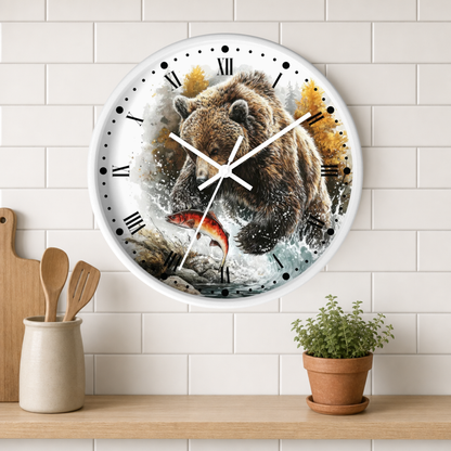 A round wall clock with a white frame and black Roman numerals, featuring a printed illustration of a brown bear catching a red fish in splashing water. The clock is mounted on a white subway tile wall above a wooden shelf with kitchen utensils and a small potted plant.