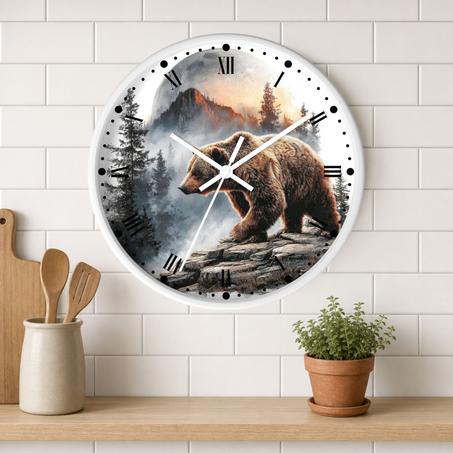 A round wall clock with a white frame and a printed scene of a brown bear in a mountain forest, mounted on a white subway tile wall above a wooden shelf with kitchen utensils and a potted plant.