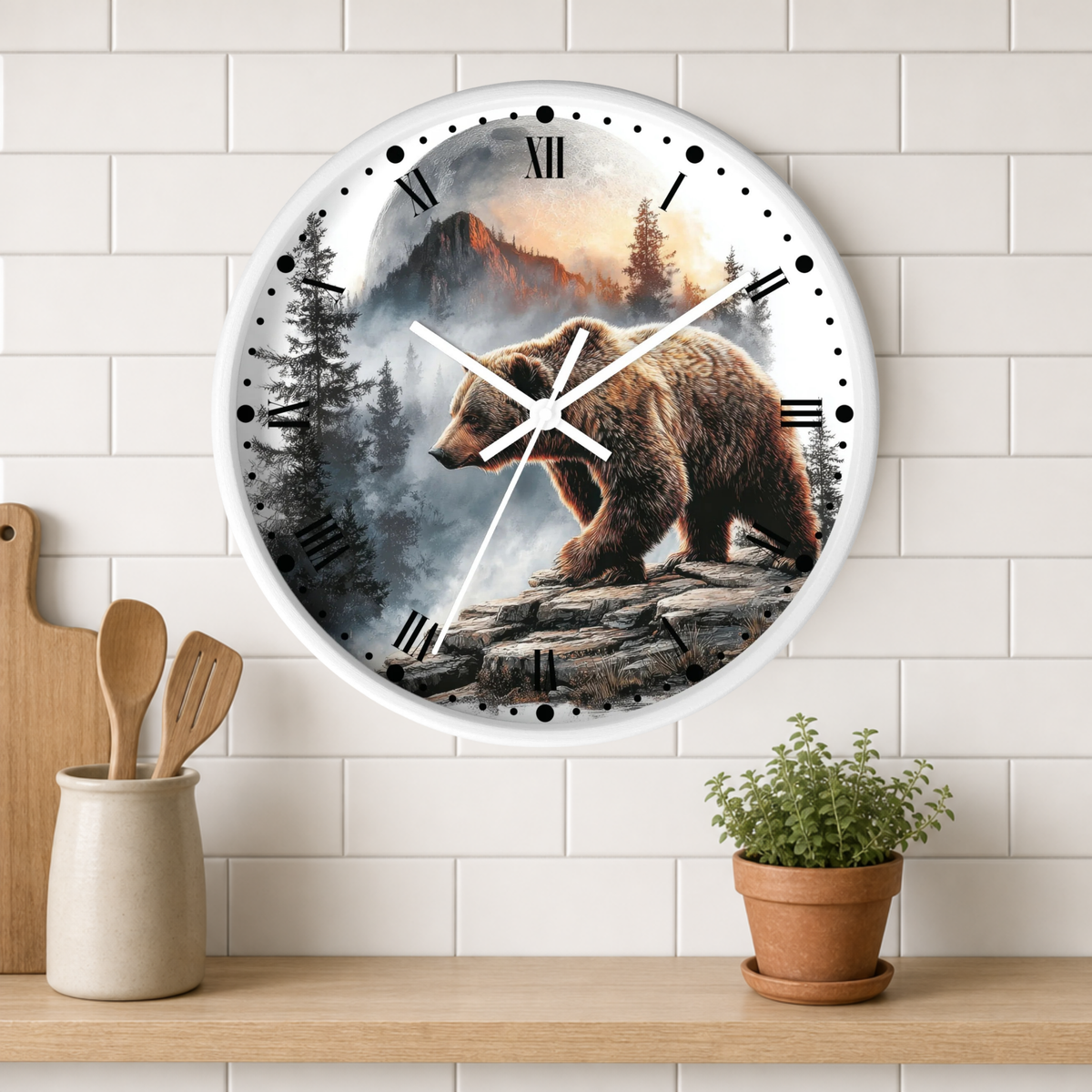 A round wall clock with a white frame and a printed scene of a brown bear in a mountain forest, mounted on a white subway tile wall above a wooden shelf with kitchen utensils and a potted plant.