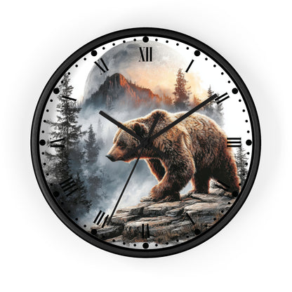 A round wall clock with a black frame and Roman numerals, featuring a detailed graphic print of a brown bear standing on a rocky cliffside with a misty mountain forest in the background.