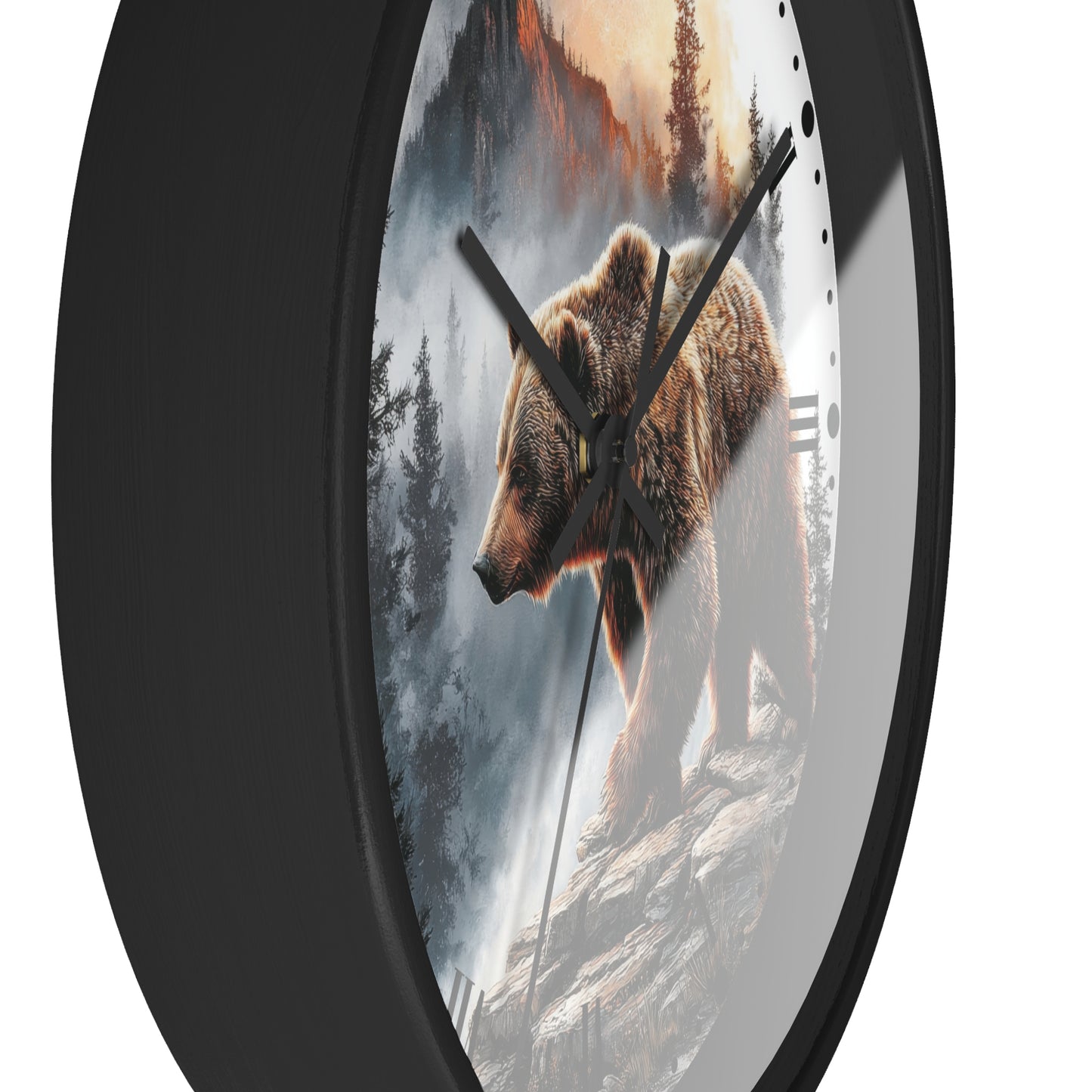 Round wall clock with a black frame and a printed design of a brown bear standing on a rocky cliffside in a misty forest landscape. The clock has black hands and a white section on the right side with small black hour markers.
