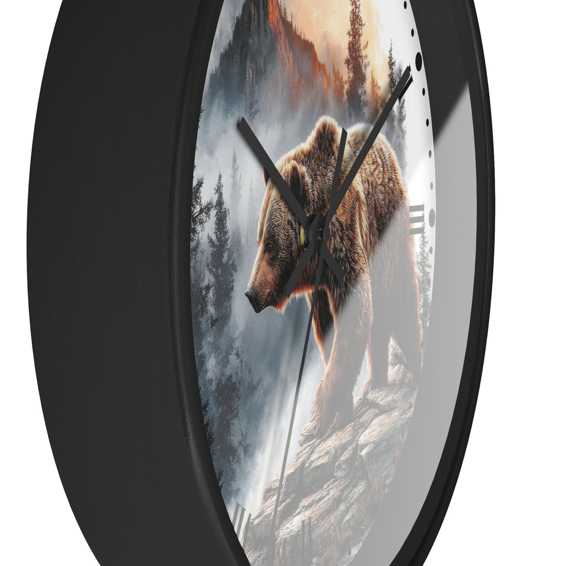 Round wall clock with a black frame and a printed design of a brown bear standing on a rocky cliffside in a misty forest landscape. The clock has black hands and a white section on the right side with small black hour markers.