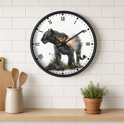 A round wall clock with a black frame and Roman numerals, featuring a detailed print of a leopard with a glowing ember on its back, mounted on a white subway tile wall above a wooden shelf with kitchen utensils and a potted plant.