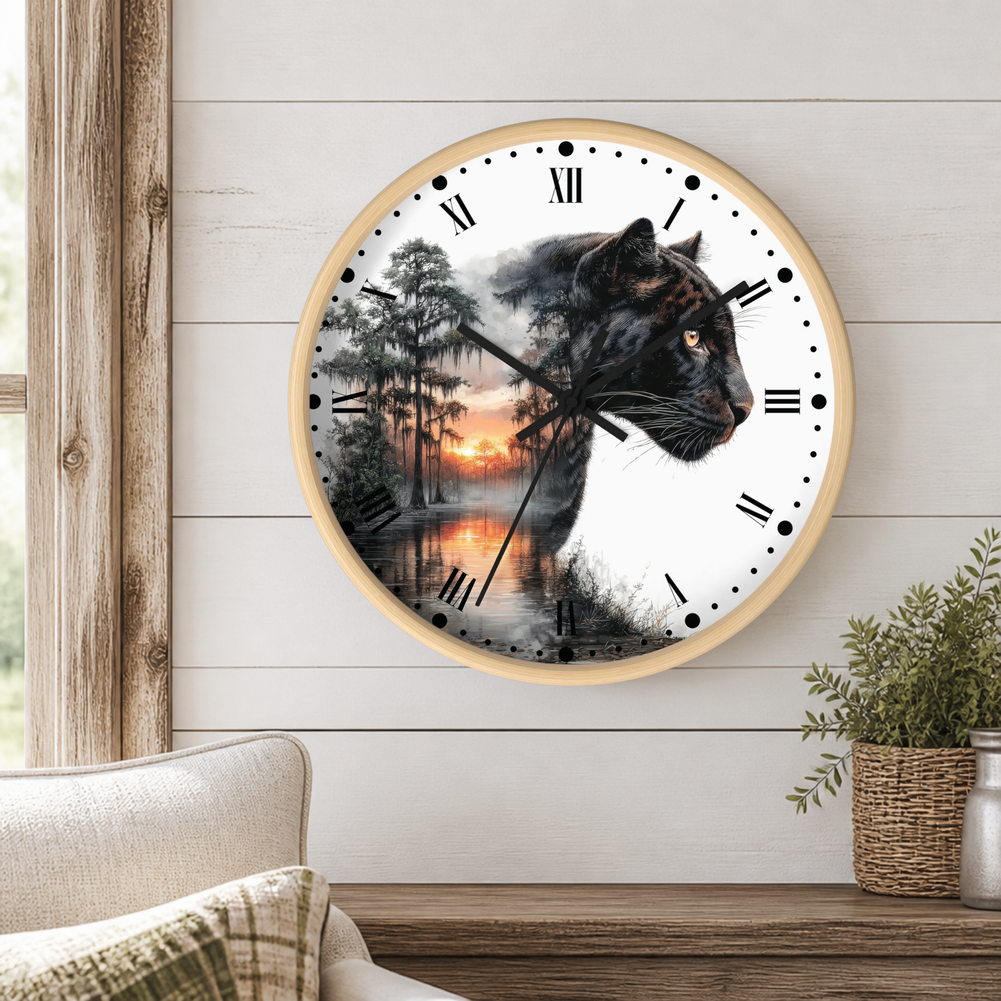 A round wall clock with a light wood frame hangs on a white shiplap wall above a wooden table. The clock face features a split design: one side shows a black panther in profile, and the other side shows a misty forest lake sunset.