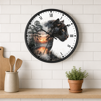 A round wall clock with a black frame hangs on a white subway-tile wall above a wooden shelf. The clock face features a black panther silhouette over a forest sunset scene.