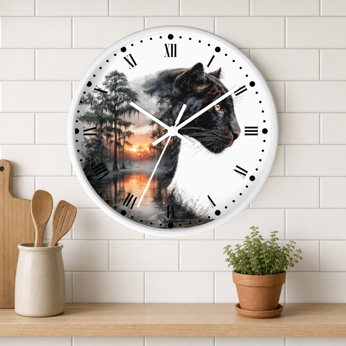 A round wall clock with a white frame and Roman numerals, featuring a printed design of a black panther over a forest sunset scene. The clock is mounted on a white subway tile wall above a wooden shelf with a small potted plant and wooden utensils.