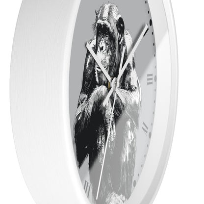 A white round wall clock featuring a black and white illustration of a chimpanzee on the face, with slim white hands and Roman numerals.