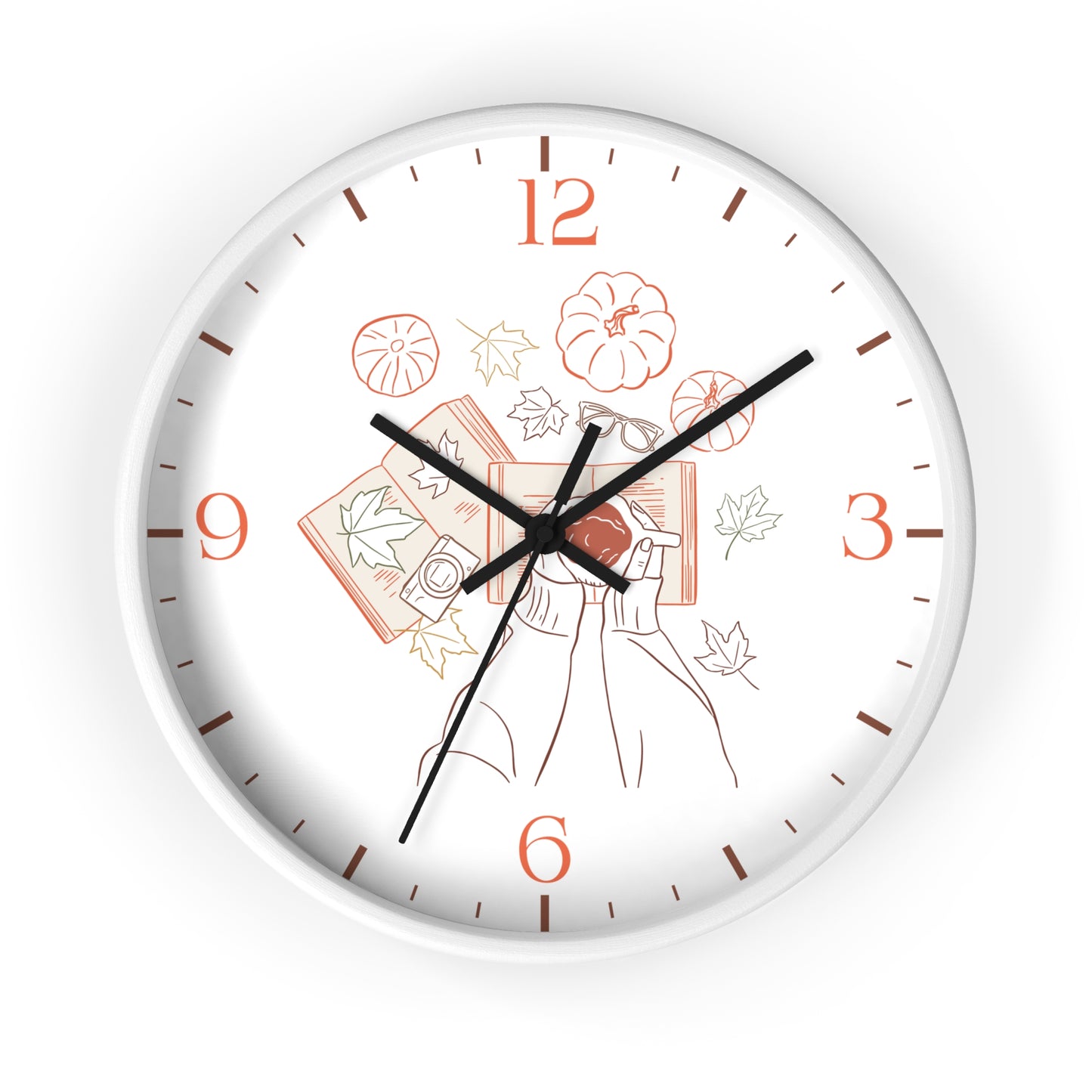 A round wall clock with a white face and outer rim, featuring black hands and orange numerals. The center of the dial has a delicate line-art illustration of a woman holding books with autumn leaves and pumpkins.