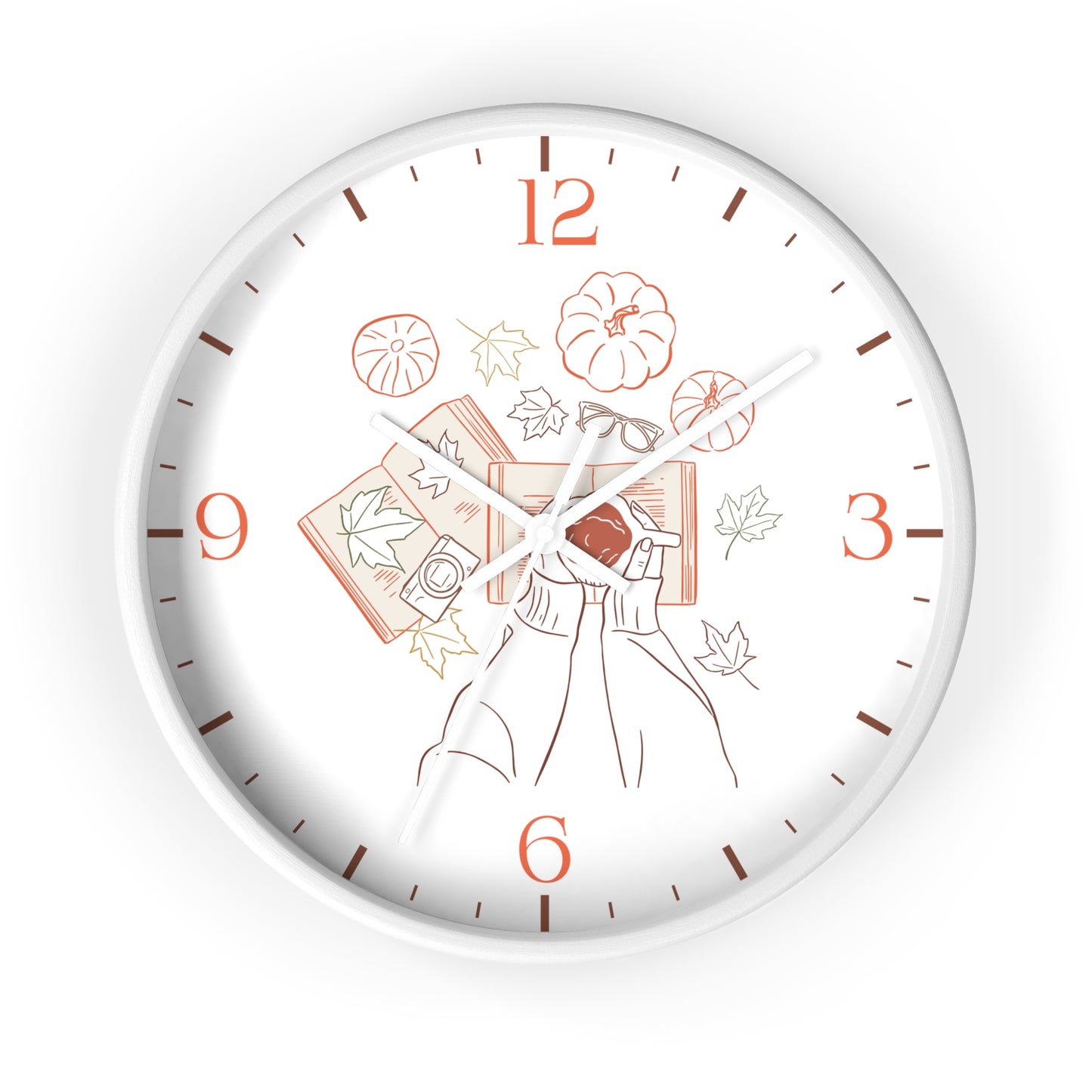 A round wall clock with a white face and silver-toned outer rim, featuring a minimalist line-art illustration of a person holding a red book surrounded by autumn leaves, pumpkins, and books in muted orange and brown tones. The numbers 1 through 9 and 6 through 12 are printed in orange, with brown minute markers and white hands.