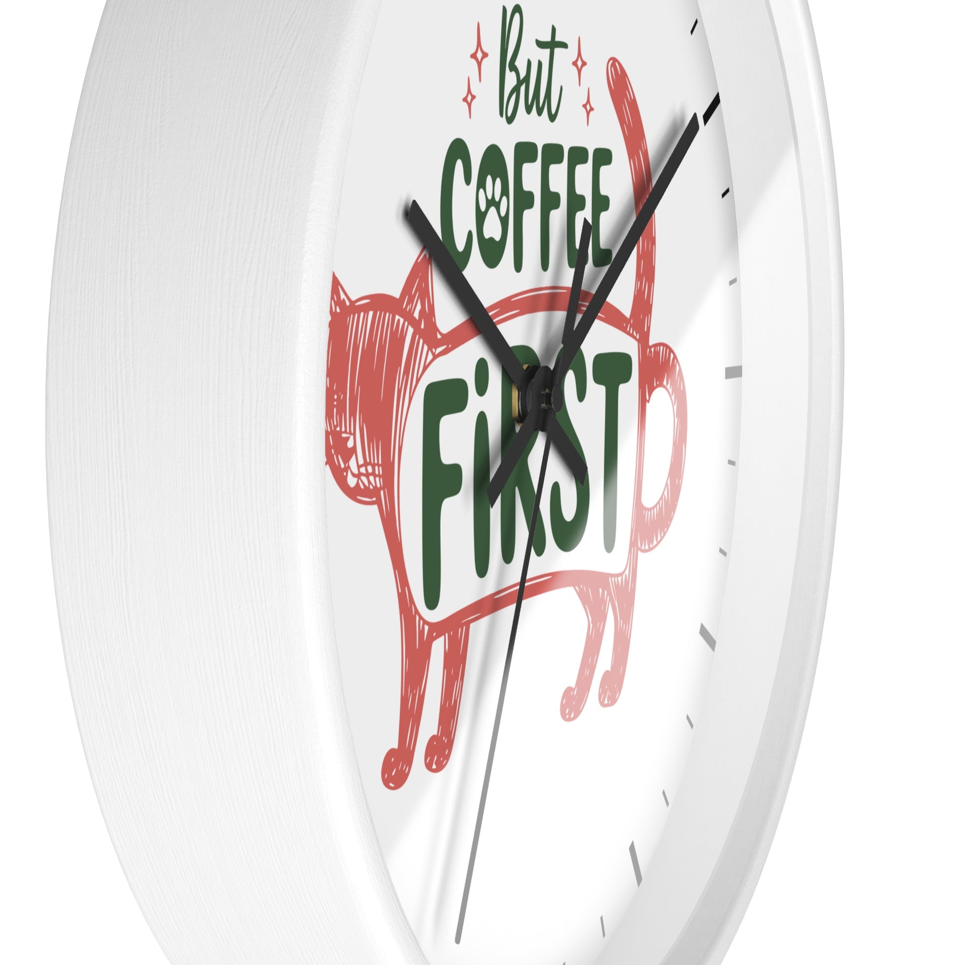 A white round wall clock with a minimalist design, featuring a red cat silhouette and the text 'But COFFEE FIRST' in green and black on the clock face.