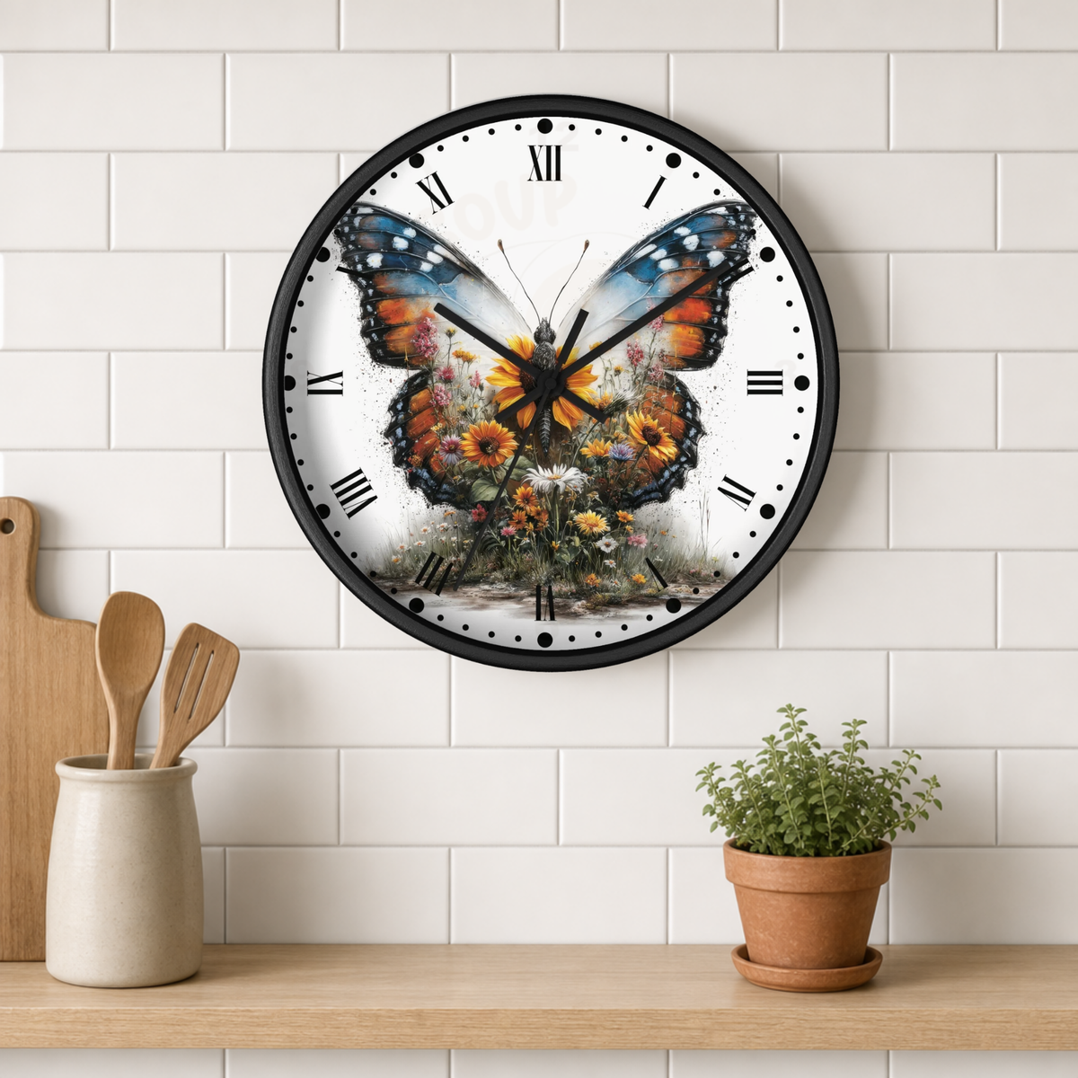 A round wall clock with a black frame hangs on a white subway-tile wall above a wooden shelf. The clock face features a large colorful butterfly with orange, blue, and black wings over a floral illustration.