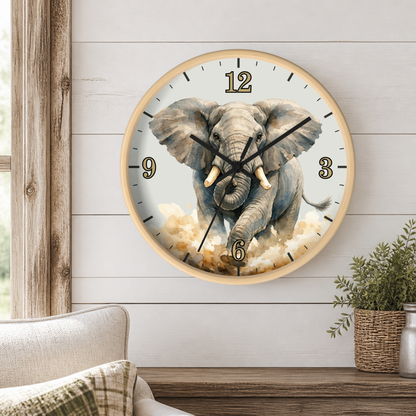 A round wall clock with a light wood frame hangs on a white shiplap wall above a wooden table. The clock face features a detailed illustration of a gray elephant emerging from clouds, with black Arabic numerals and black hands.