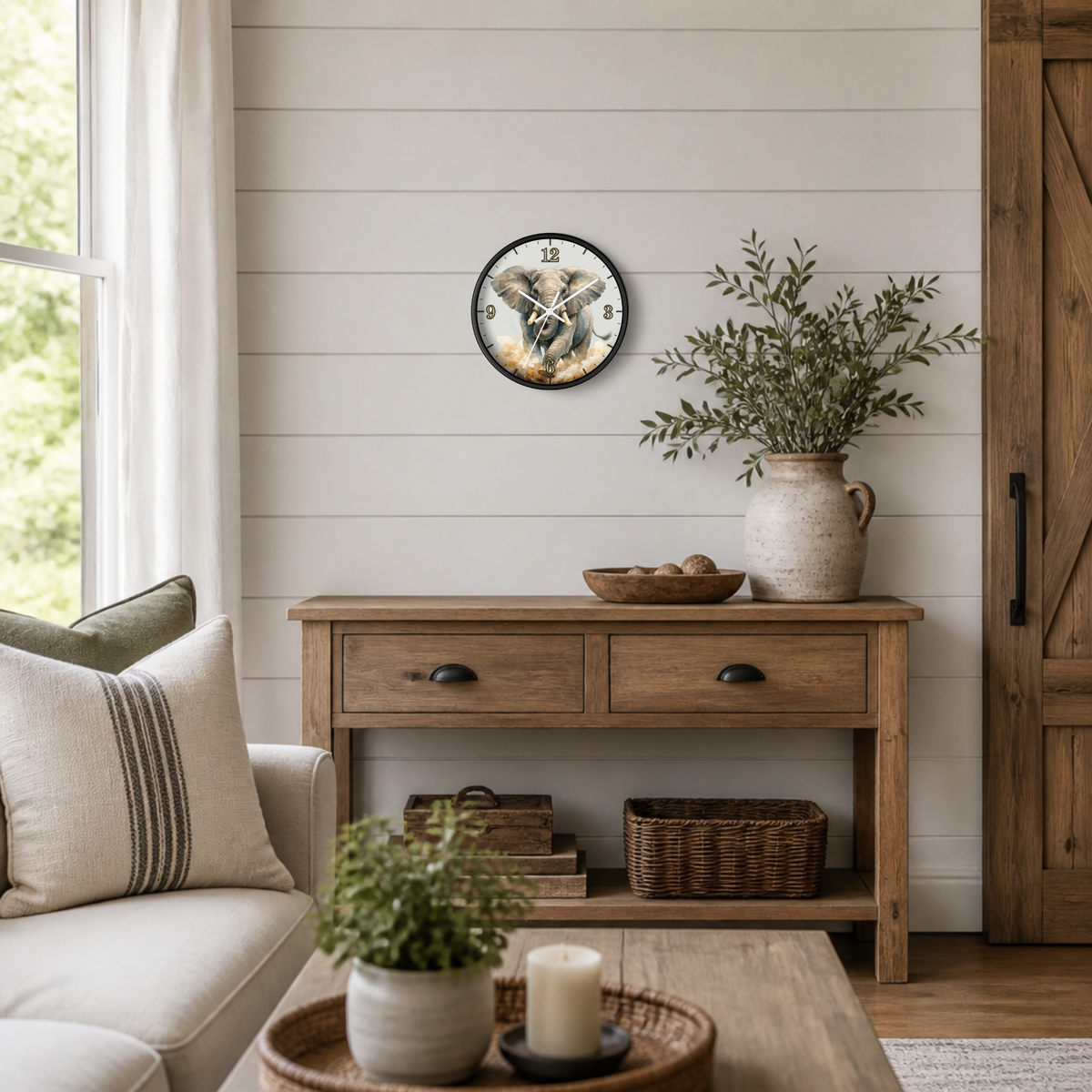 A round wall clock with a rustic illustration of a African elephant , styled on a white shiplap wall above a wooden console table in a bright, modern farmhouse living room.