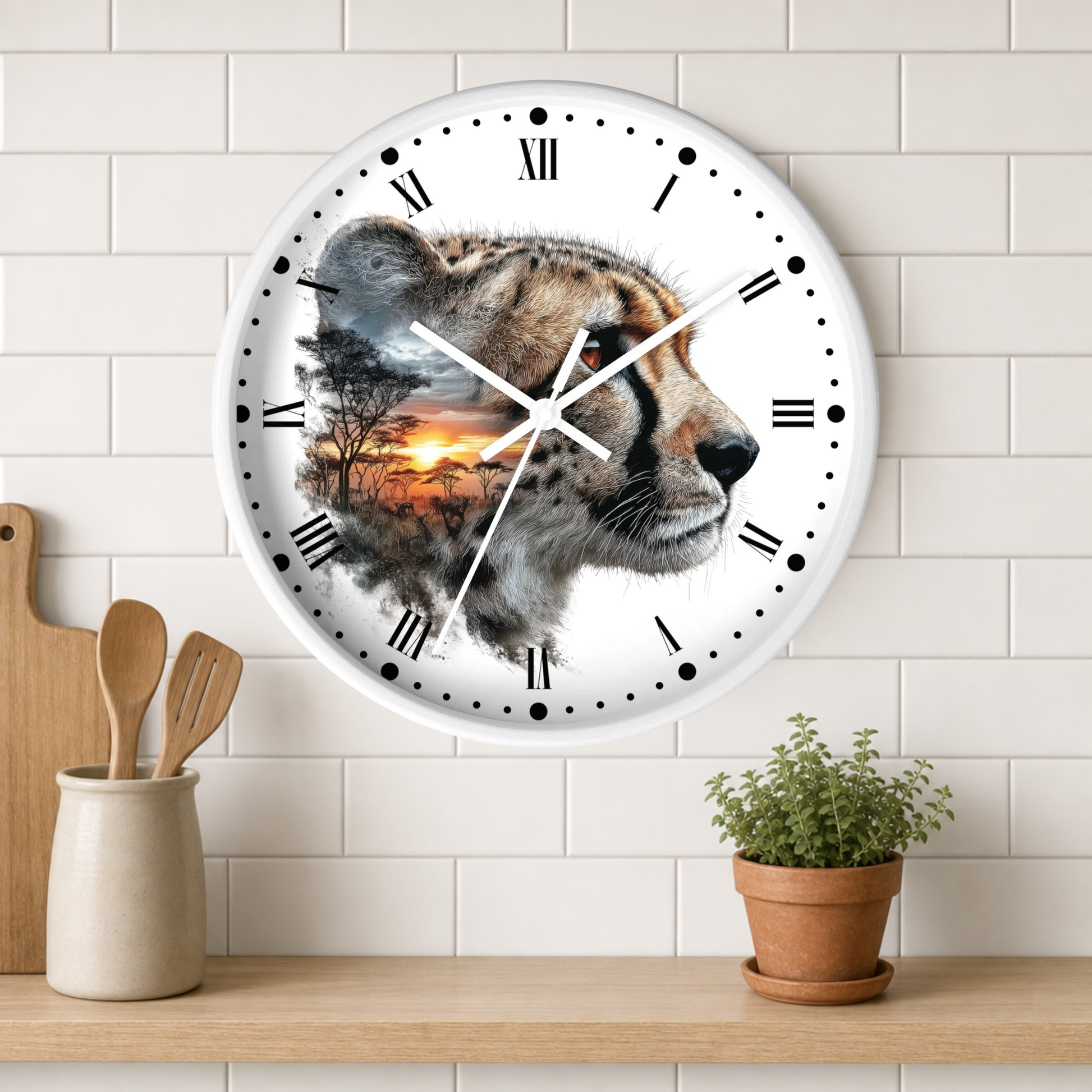A round wall clock with a white face and black Roman numerals, featuring a photographic cheetah profile with a sunset landscape printed inside one eye. The clock is mounted on a white subway-tile wall above a wooden shelf with kitchen utensils and a potted plant.