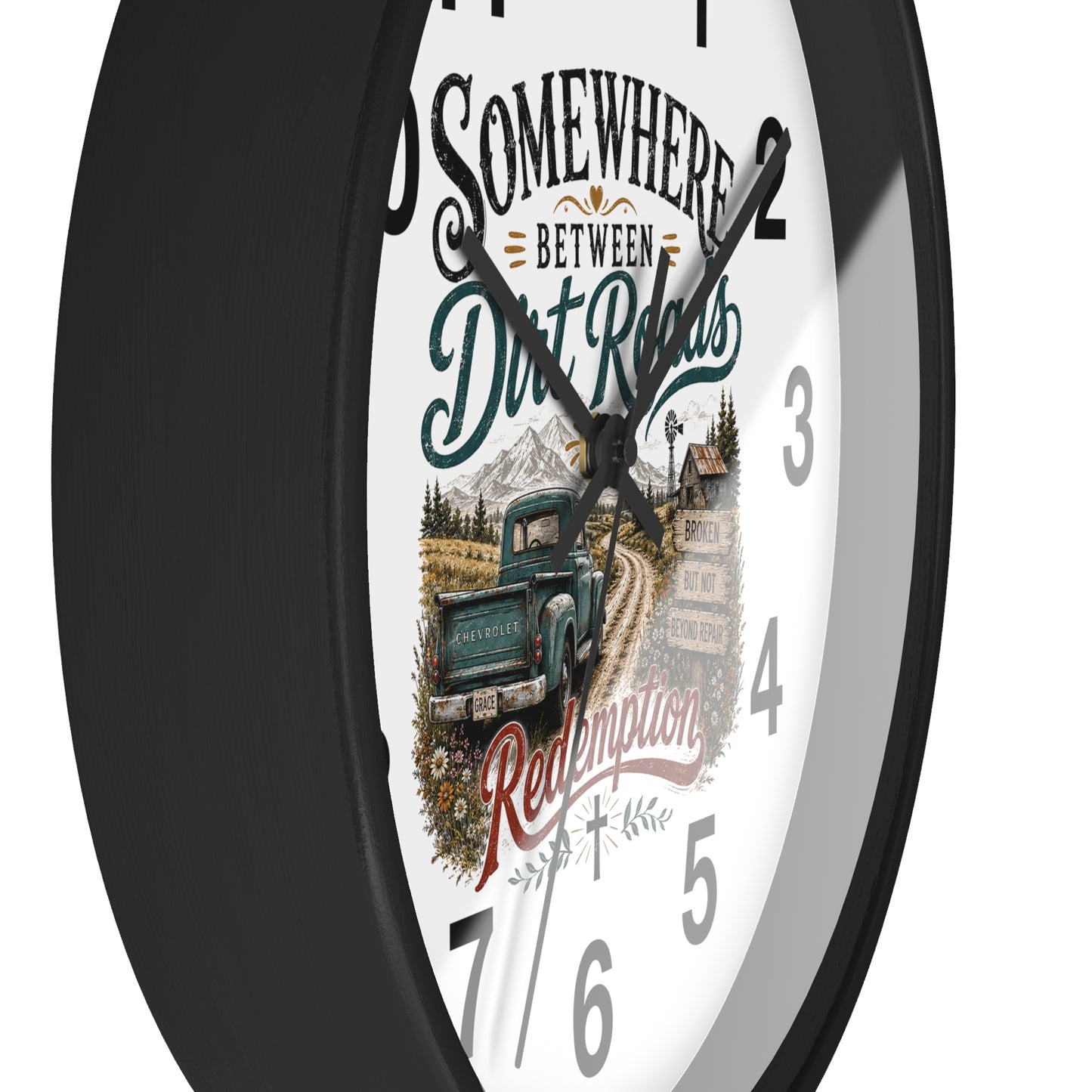 A round wall clock with a black frame and a white face featuring a vintage truck illustration and the text 'Somewhere Between Dirt Roads Redemption'.