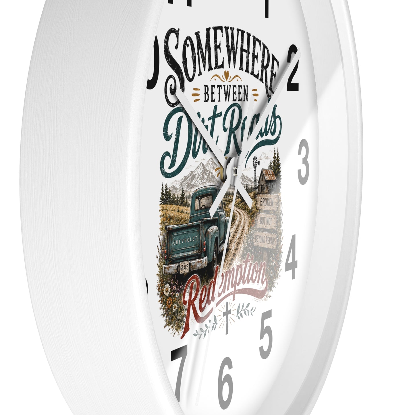 A white round wall clock with a rustic western-themed dial design featuring the text 'Somewhere Between Dirt Roads Red Emporia' and an illustration of a vintage pickup truck on a dirt road.