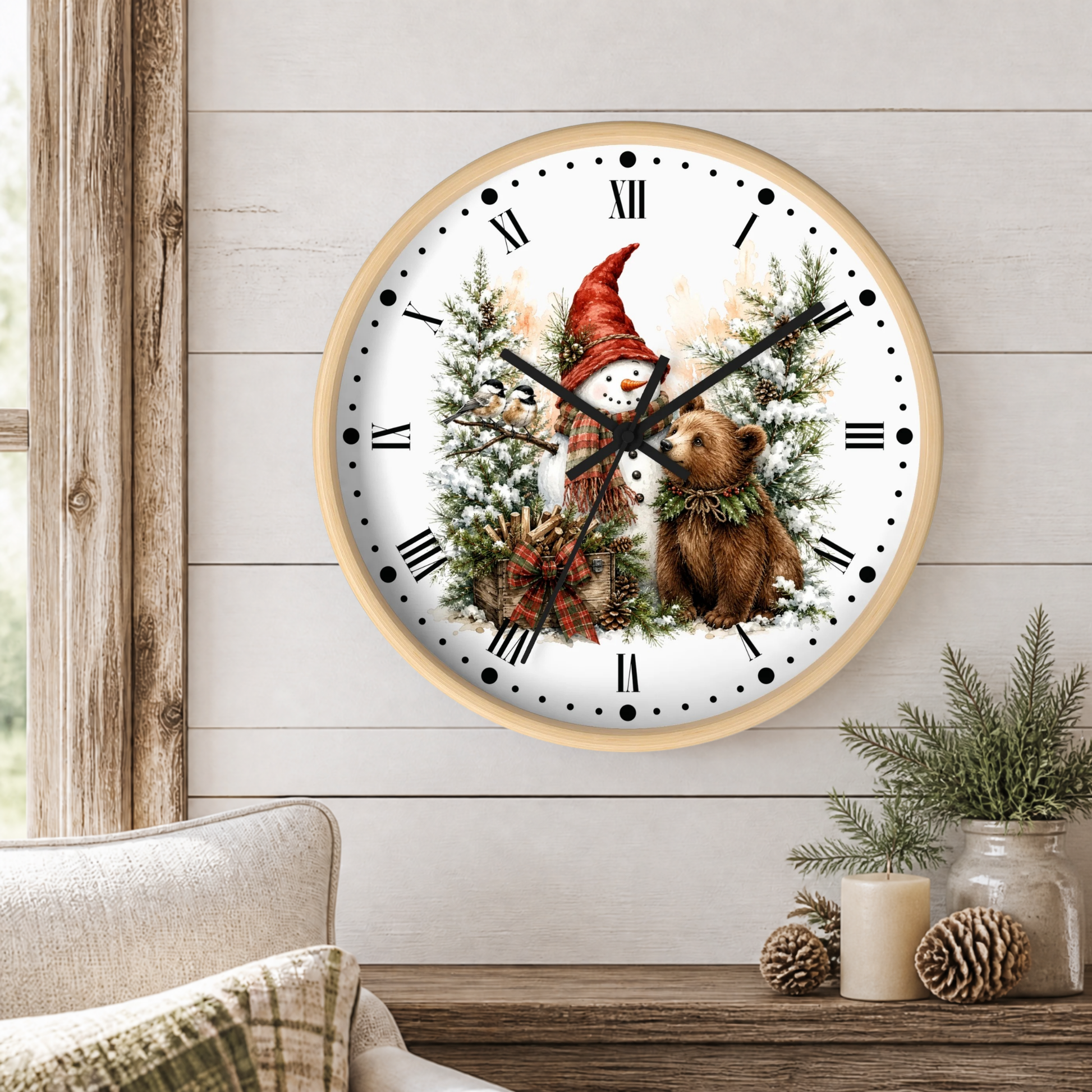 A round wall clock with a light wood frame hangs on a white shiplap wall above a rustic table. The clock face features a winter holiday illustration with a snowman in a red hat, a brown bear, pine trees, and black Roman numerals.