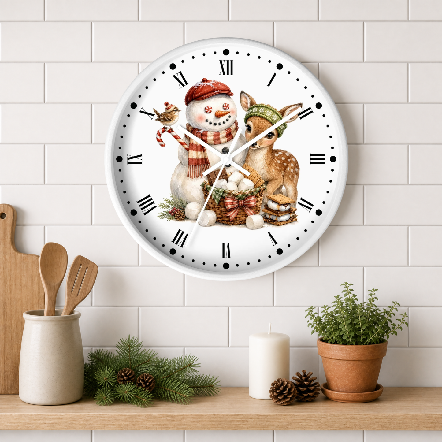A round white wall clock with a festive illustration of a snowman and a deer on the face, mounted on a white subway tile wall above a wooden shelf with candles, pinecones, and a potted plant.
