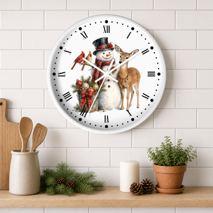 A round white wall clock with a festive Christmas illustration of a snowman, deer, bird, and red cardinal, mounted on a white subway tile wall above a wooden shelf with kitchen decor.