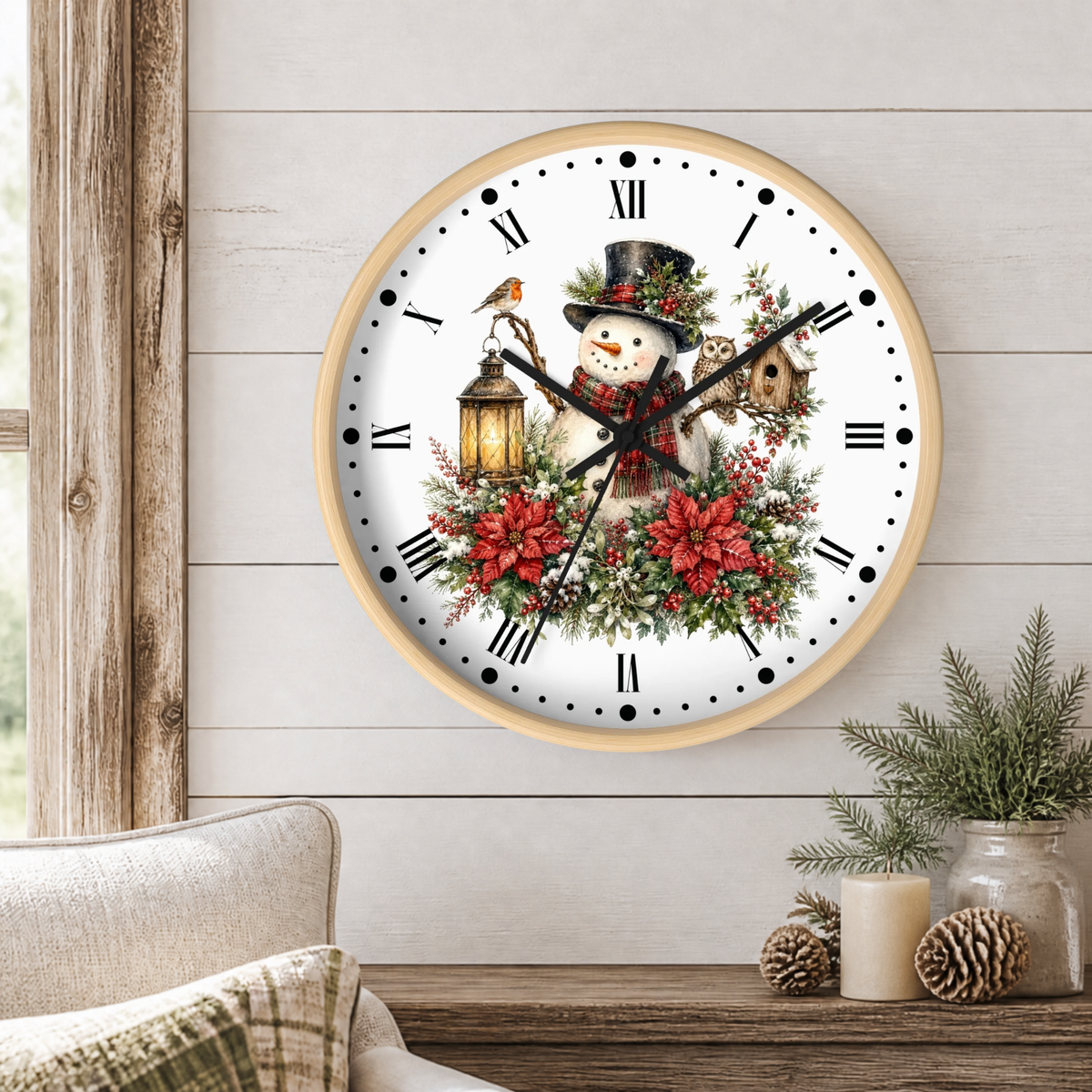 A round wall clock with a light wood frame hangs on a white shiplap wall above a rustic wooden table. The clock face features a festive winter illustration with a snowman wearing a black top hat and red scarf, surrounded by red poinsettias, green holly leaves, a bird perched on a lantern, an owl, and a small birdhouse.