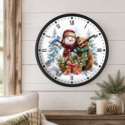 A round wall clock with a black frame and a festive winter illustration of a snowman, blue jay, and a bear, displayed on a light wood paneled wall above a wooden table with holiday decor.