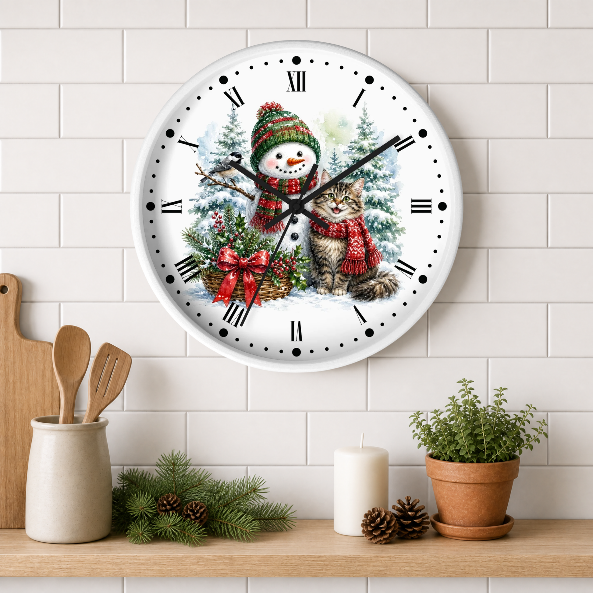 A round wall clock with a festive Christmas illustration of a snowman and a cat, mounted on a white subway tile wall above a wooden shelf with kitchen decor.