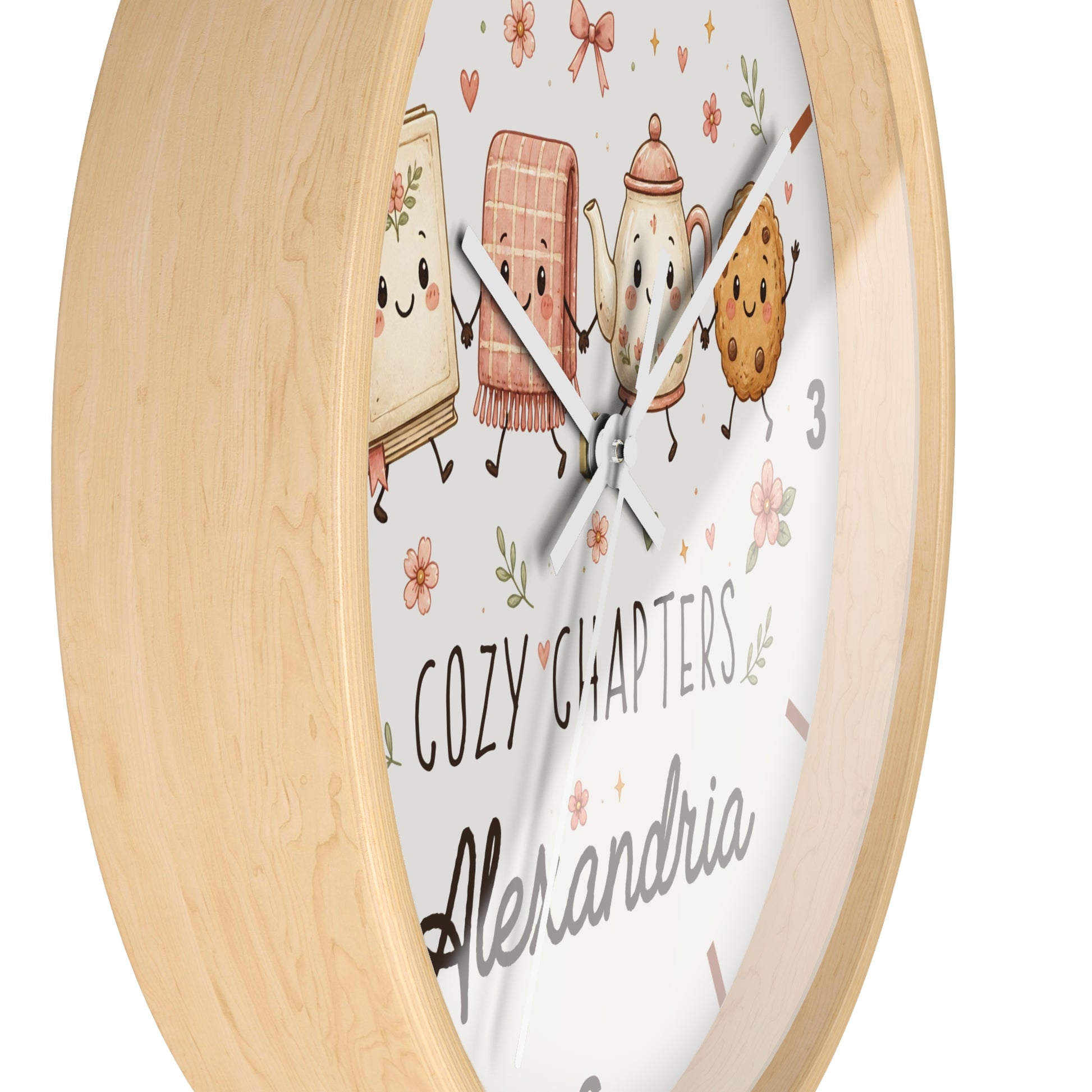 A round wooden wall clock with a light natural wood frame and a white face featuring cute illustrated characters and the text 'COZY CHAPTERS' and 'Alexandria'.
