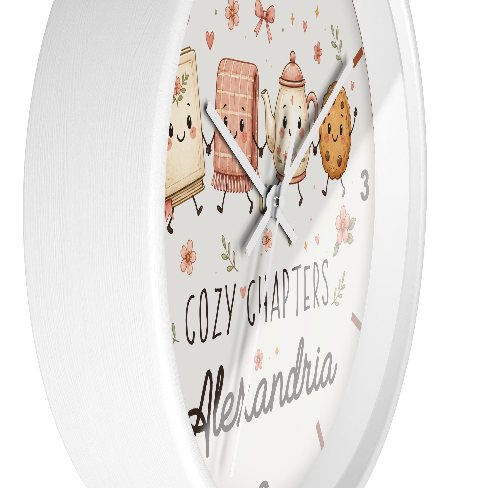 A round white wall clock with a whimsical illustrated face showing cute characters and the text 'COZY CHAPTERS' and 'Alexandria'.