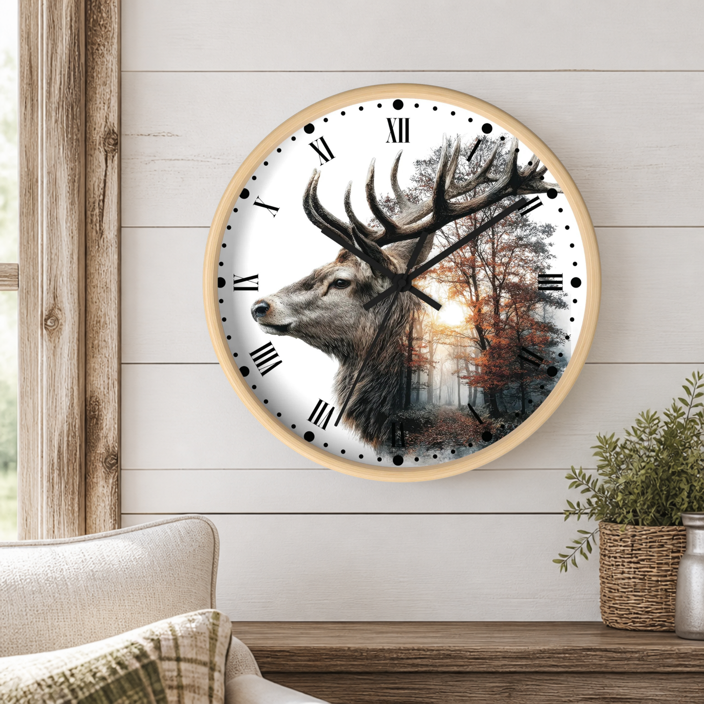A round wall clock with a light wood frame hangs on a white shiplap wall above a wooden mantel. The clock face features a detailed illustration of a stag deer head with large antlers, set against a forest scene with autumn trees.