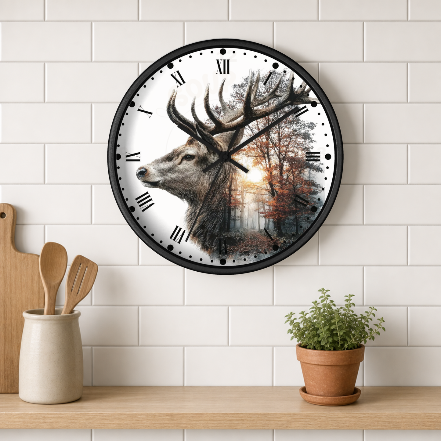 A round wall clock with a black frame hangs on a white subway-tile wall above a wooden shelf. The clock face features a detailed illustration of a deer head with large antlers in profile, set against a forest scene with warm sunlight.