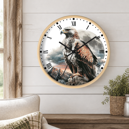 A round wall clock with a light wood frame and a printed design of a large eagle perched on a rocky cliff under a cloudy sky. The clock is mounted on a white shiplap wall above a wooden table with a potted plant and part of a sofa visible.