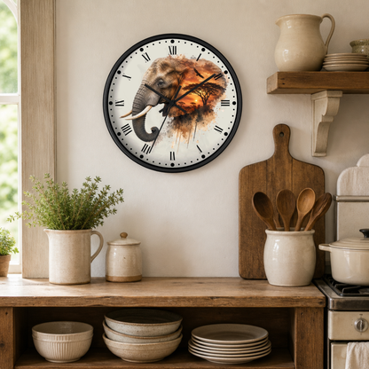 A round wall clock with a black frame and a printed elephant illustration on the face, hanging on a beige wall in a rustic kitchen setting with wooden shelves, ceramic dishes, and plants.