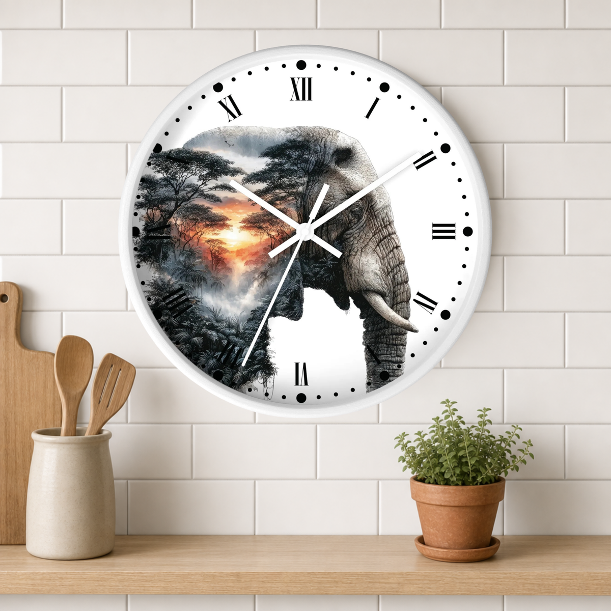 A round wall clock with a white face and Roman numerals, featuring a printed design of an elephant over a misty forest and fiery sunset. The clock is mounted on a white subway tile wall above a wooden shelf with a small potted plant and wooden utensils.