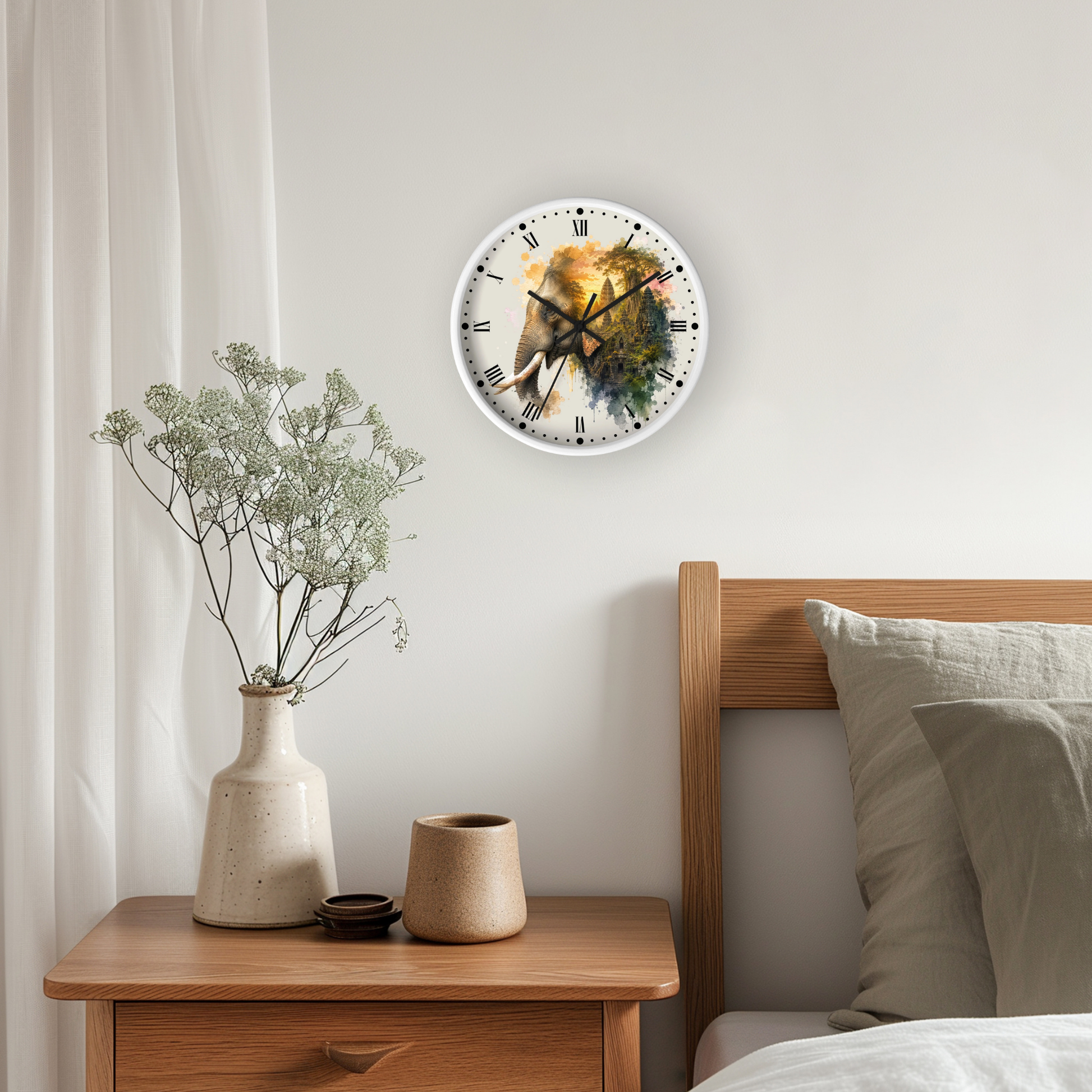 A round wall clock with a watercolor-style elephant illustration hangs on a light gray wall above a wooden nightstand in a bedroom setting.