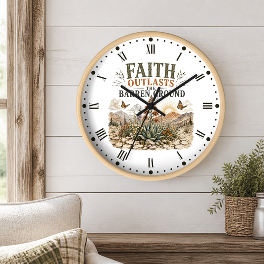 A round wall clock with a light wood frame hangs on a white shiplap wall above a wooden table. The clock face is white with black Roman numerals, black hands, and a central illustration featuring the text 'FAITH OUTLASTS THE BARREN LAND' above a desert landscape with a sun, mountains, and cacti.