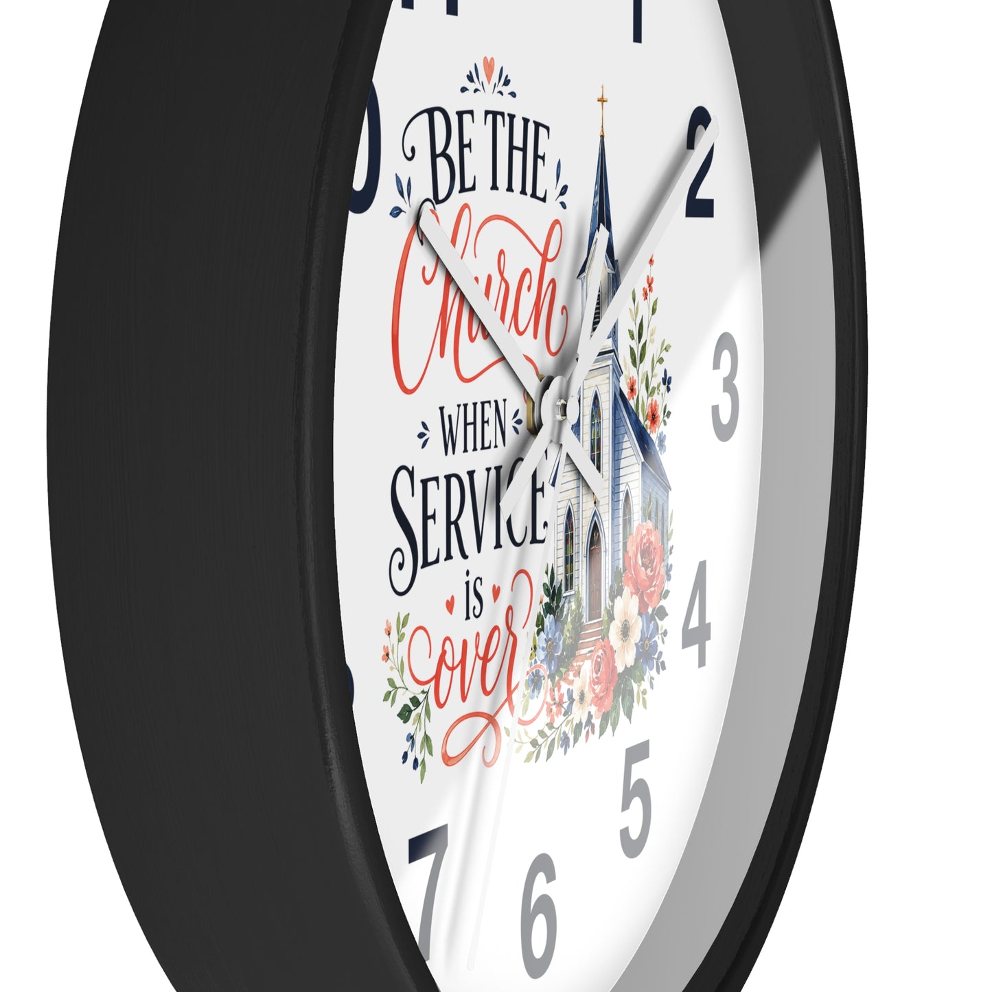 A round wall clock with a black frame and a white face featuring the phrase 'Be the Church When Service is Over' in black and coral script, alongside an illustration of a church and floral details.